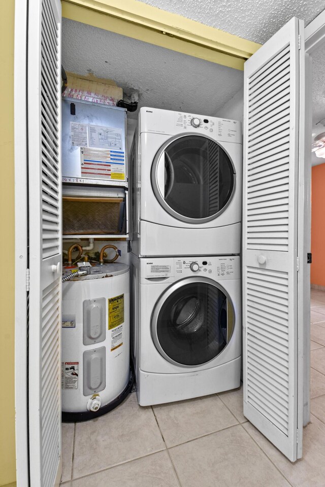 laundry room featuring a textured ceiling, light tile patterned flooring, and stacked washer / dryer