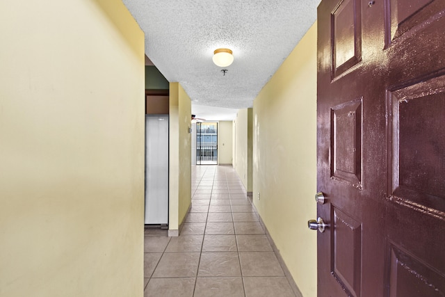 hall featuring a textured ceiling and light tile patterned floors