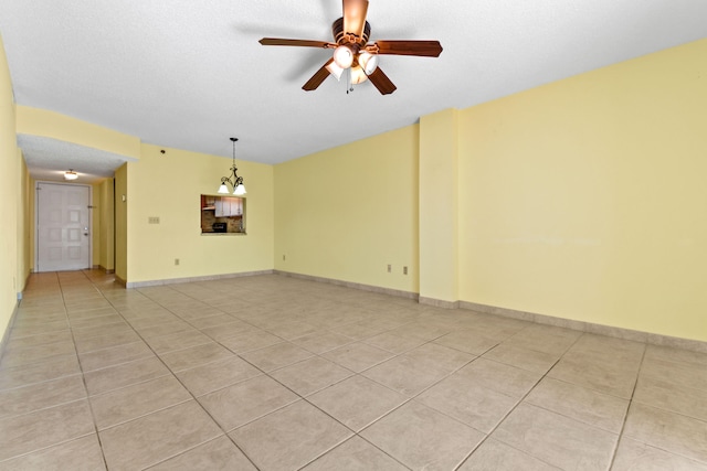 empty room with a textured ceiling, ceiling fan, and light tile patterned flooring