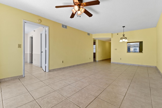 tiled spare room with a textured ceiling and ceiling fan with notable chandelier