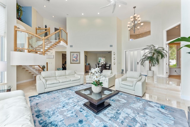 living room featuring a towering ceiling and ceiling fan with notable chandelier