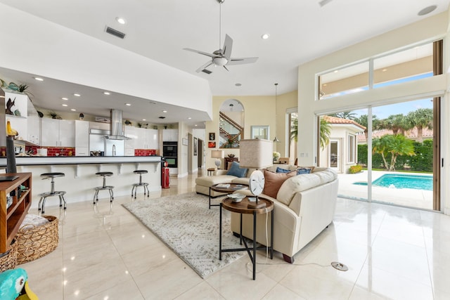 living room featuring ceiling fan, a towering ceiling, and light tile patterned floors