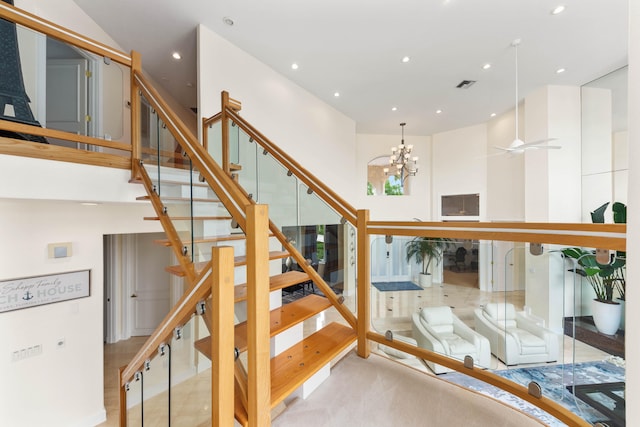 staircase with ceiling fan with notable chandelier