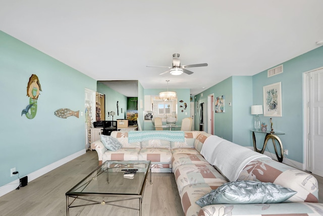 living room with light hardwood / wood-style floors and ceiling fan with notable chandelier