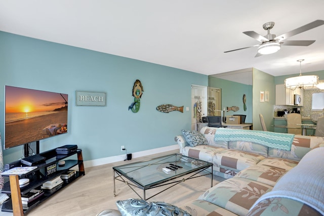 living room featuring light wood-type flooring and ceiling fan with notable chandelier