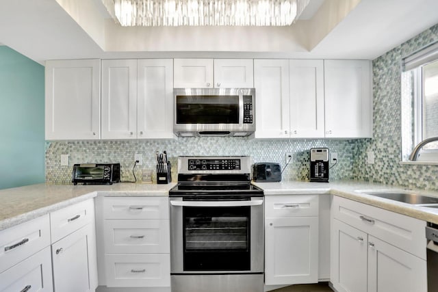 kitchen featuring stainless steel appliances, white cabinetry, sink, and decorative backsplash