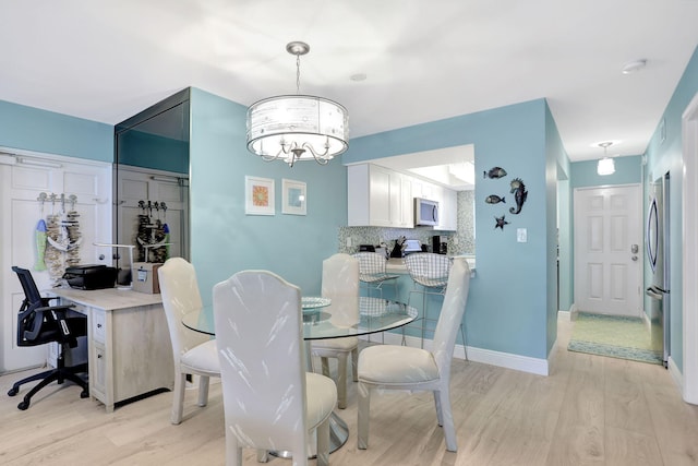 dining space featuring light wood-type flooring and a notable chandelier