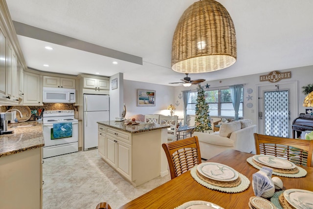 kitchen with cream cabinets, ceiling fan, stone counters, white appliances, and tasteful backsplash