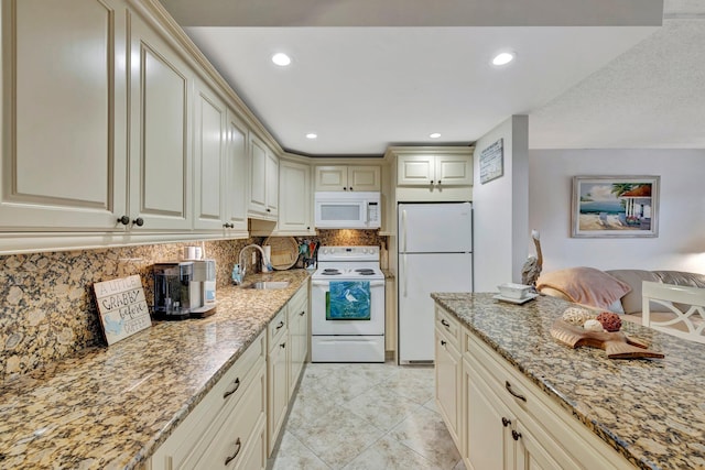 kitchen with cream cabinets, light stone countertops, and white appliances