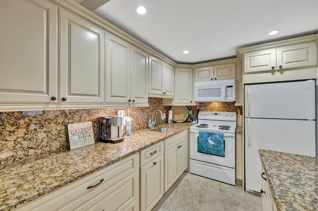 kitchen with cream cabinets, tasteful backsplash, light stone countertops, sink, and white appliances