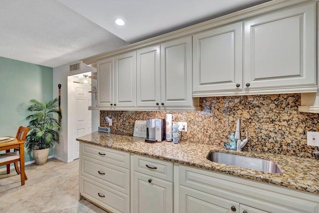 kitchen featuring light stone countertops, sink, a textured ceiling, decorative backsplash, and light tile patterned floors