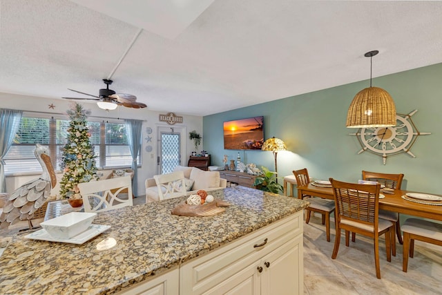 kitchen featuring decorative light fixtures, light tile patterned floors, light stone counters, a textured ceiling, and ceiling fan