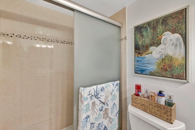 bathroom featuring a shower with door and toilet