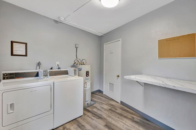 laundry area with electric water heater, hardwood / wood-style flooring, and separate washer and dryer