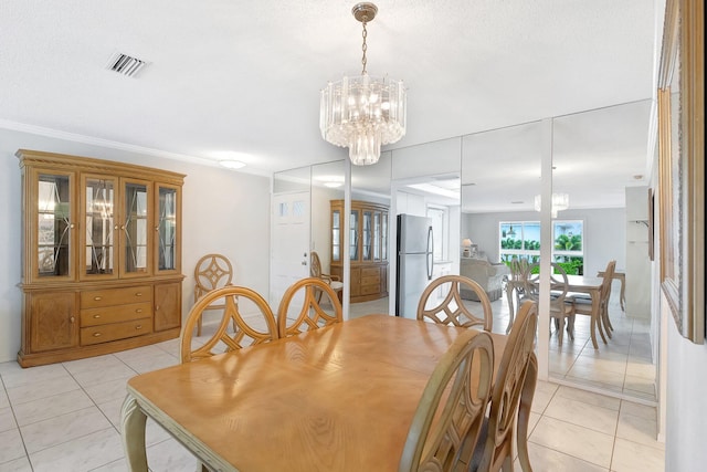 tiled dining space featuring ornamental molding, a textured ceiling, and an inviting chandelier