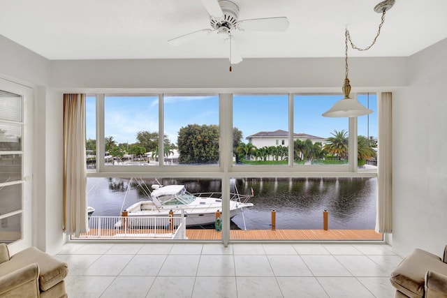 sunroom / solarium with ceiling fan and a water view