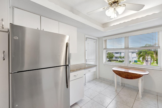 kitchen featuring stainless steel refrigerator, white cabinetry, light stone countertops, ceiling fan, and light tile patterned floors