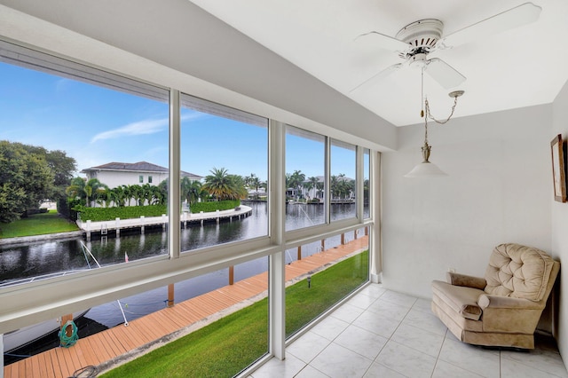 sunroom / solarium with ceiling fan and a water view