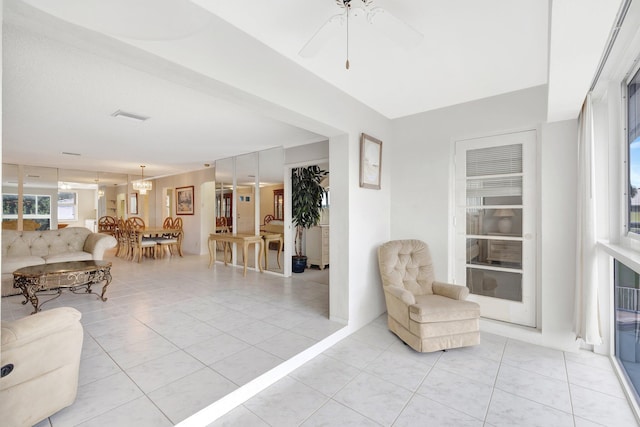 sitting room with ceiling fan with notable chandelier and light tile patterned flooring