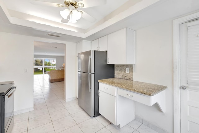 kitchen featuring light stone countertops, backsplash, stainless steel appliances, a tray ceiling, and white cabinets