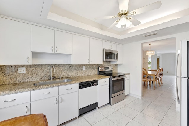 kitchen featuring a raised ceiling, white cabinetry, sink, and appliances with stainless steel finishes