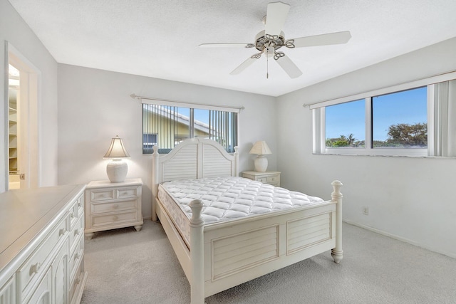 carpeted bedroom featuring multiple windows, ceiling fan, and a textured ceiling