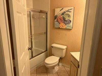 full bathroom with vanity, bath / shower combo with glass door, toilet, and tile patterned flooring