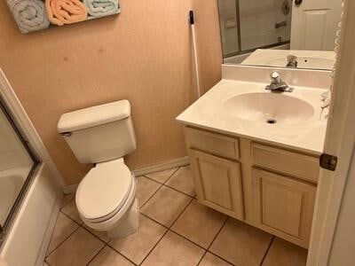 full bathroom featuring vanity, bath / shower combo with glass door, toilet, and tile patterned flooring