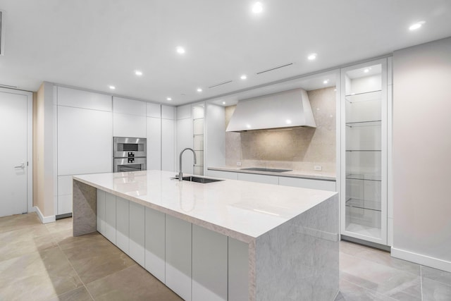 kitchen featuring custom exhaust hood, sink, black electric cooktop, and a large island