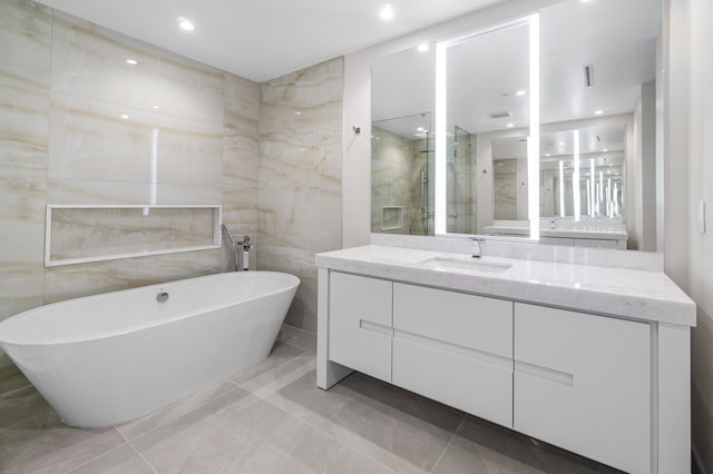 bathroom with tile walls, vanity, and independent shower and bath