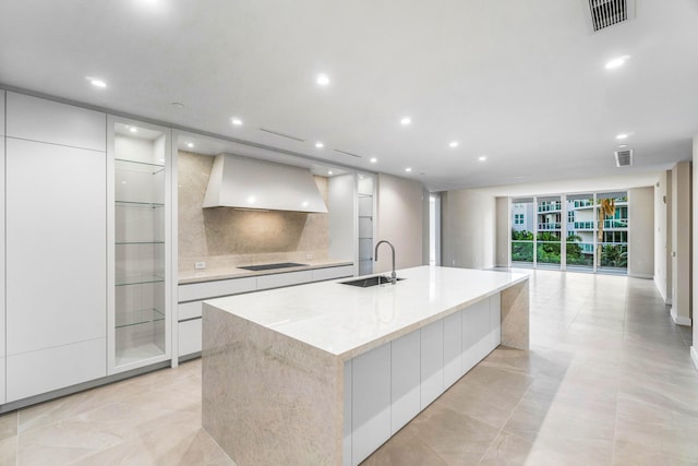 kitchen featuring premium range hood, a spacious island, sink, white cabinetry, and black electric stovetop