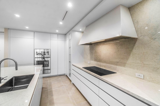 kitchen featuring black electric stovetop, custom range hood, sink, and white cabinets