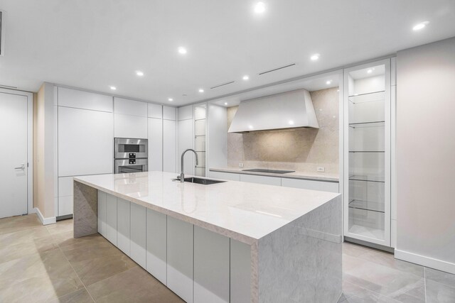 kitchen with black electric cooktop, a large island, sink, and custom range hood