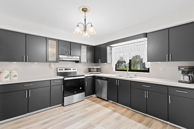 kitchen featuring appliances with stainless steel finishes, sink, light hardwood / wood-style floors, a notable chandelier, and decorative light fixtures