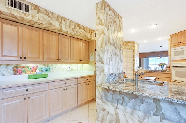 kitchen featuring white appliances, pendant lighting, a notable chandelier, light tile patterned floors, and light brown cabinets