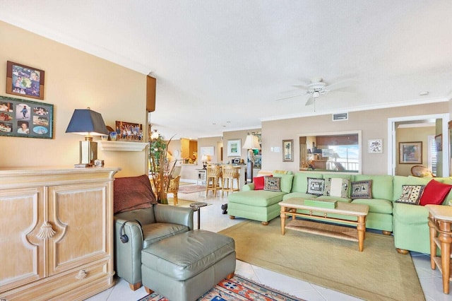 living room featuring ceiling fan, a textured ceiling, ornamental molding, and light tile patterned flooring