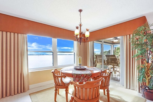 dining space featuring an inviting chandelier, a textured ceiling, a water view, and light tile patterned floors