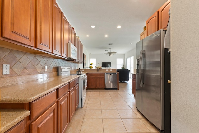 kitchen featuring stainless steel appliances, light tile patterned flooring, ceiling fan, light stone counters, and tasteful backsplash