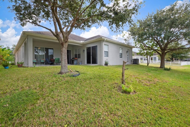 rear view of property with cooling unit and a lawn