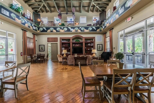 dining area featuring french doors, hardwood / wood-style flooring, beamed ceiling, and a high ceiling