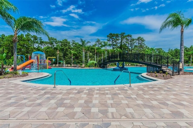 view of pool featuring a water slide, a patio, and a playground