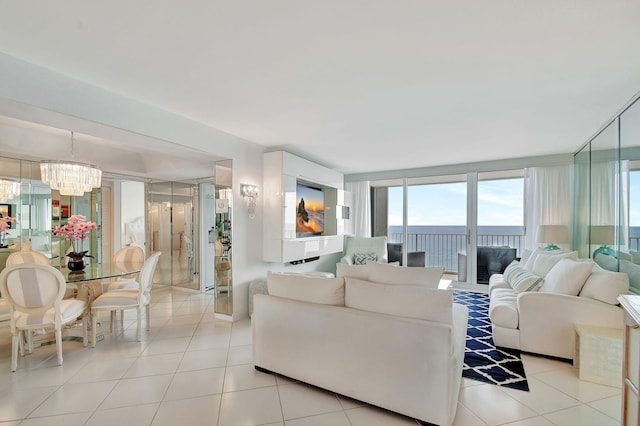 tiled living room featuring a water view, an inviting chandelier, and a wall of windows