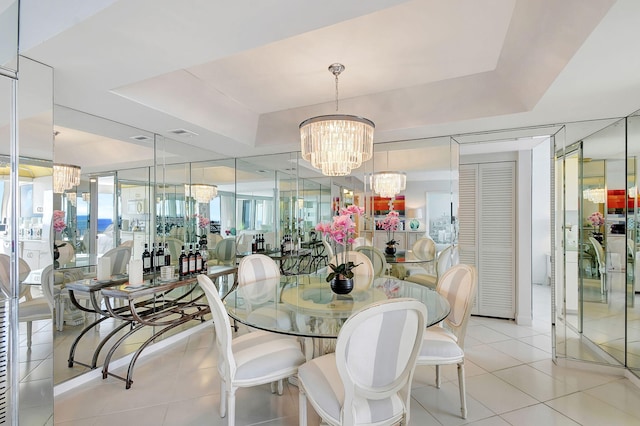 dining room featuring a raised ceiling, light tile patterned flooring, and a chandelier