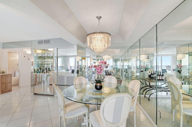 tiled dining room featuring a raised ceiling and a chandelier