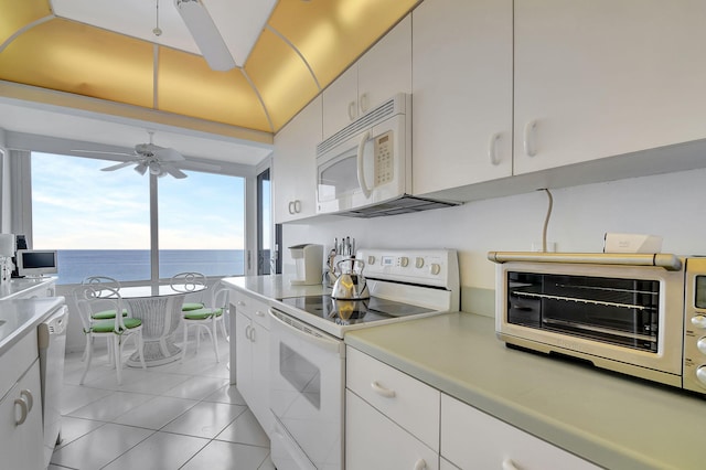 kitchen with white appliances, light tile patterned flooring, white cabinetry, ceiling fan, and a water view