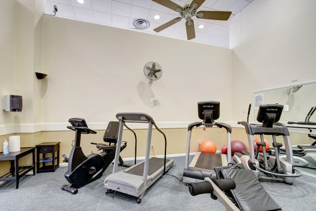 exercise area with ceiling fan and a high ceiling