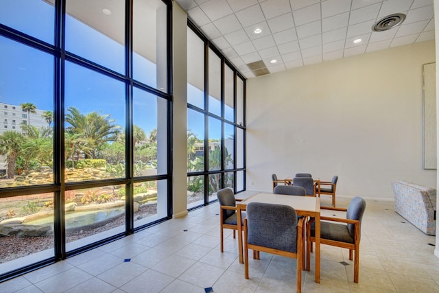 dining room featuring a towering ceiling, light tile patterned floors, and floor to ceiling windows