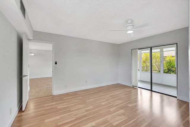 empty room with light hardwood / wood-style flooring, a textured ceiling, and ceiling fan with notable chandelier