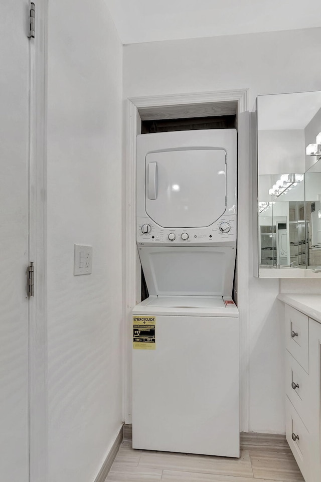 clothes washing area featuring light hardwood / wood-style flooring and stacked washer and dryer