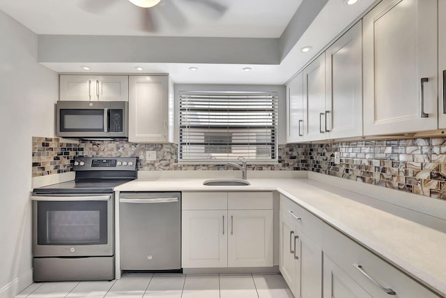 kitchen with appliances with stainless steel finishes, sink, light tile patterned floors, and backsplash